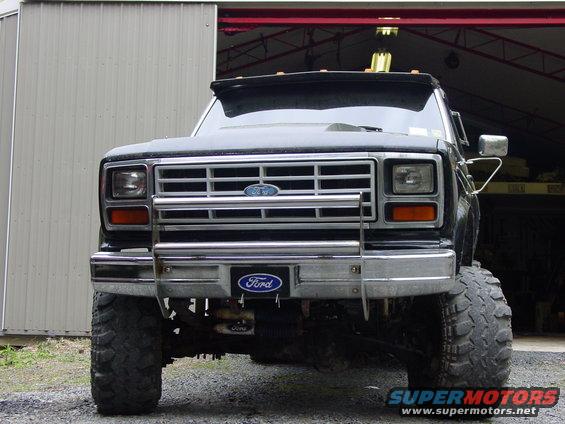 Front view of a lifted black Ford pickup truck with a chrome grille guard and large tires