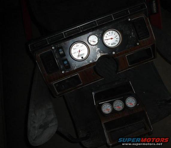 Dashboard trim with three gauges and a tachometer, showing wood grain accents