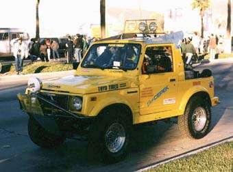 Yellow Suzuki Samurai with off-road modifications, including a brush guard and roof lights