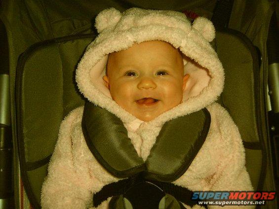 Baby wearing a pink hooded outfit with bear ears, sitting in a stroller