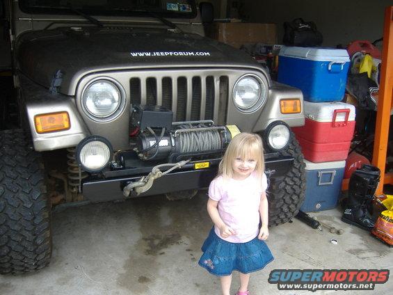 Front view of a 2004 Jeep Wrangler with a winch, a young girl stands beside it