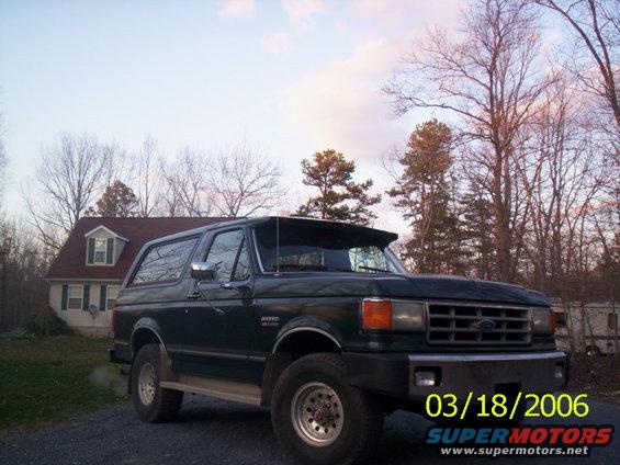 Dark green Ford Bronco parked in a driveway with a house and trees in the background. Date stamp reads 03/18/2006