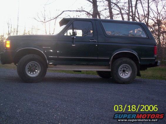 Side view of a dark green 1988 Ford Bronco with aftermarket wheels