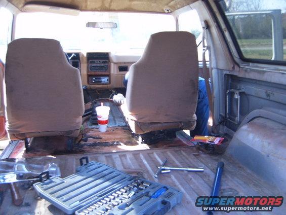Interior view of a truck with seats removed, showing a toolbox and a drink cup on the floor