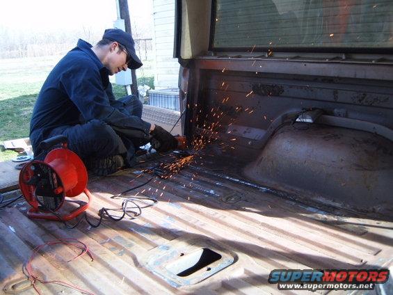 guy grinding metal in the bed of a pickup truck, sparks flying