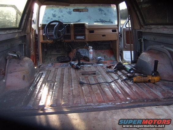 Disassembled interior of a brown 1980s Ford Bronco with tools on the floor