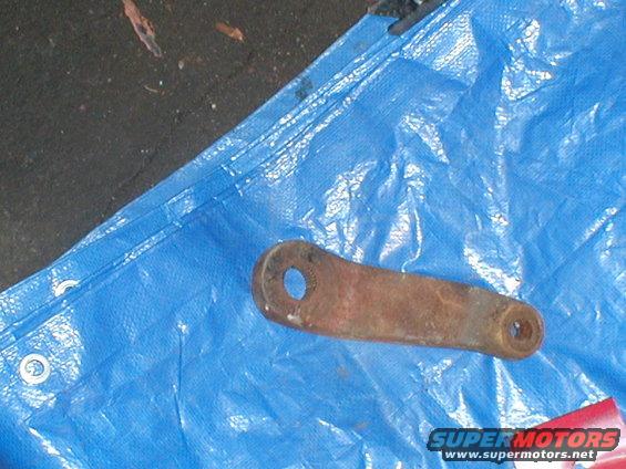 Rusty metal linkage part with two holes on blue tarp