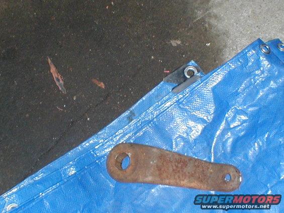 Rusty metal bracket with two holes on a blue tarp