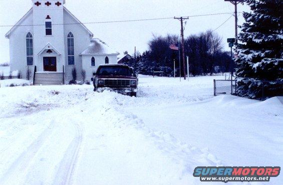 Red SUV stuck in snow, front view. Appears to be from the early 1980s