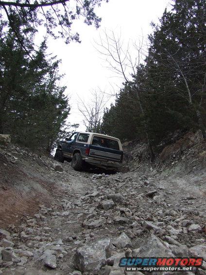Rear view of a 1986 Ford Bronco climbing a rocky trail