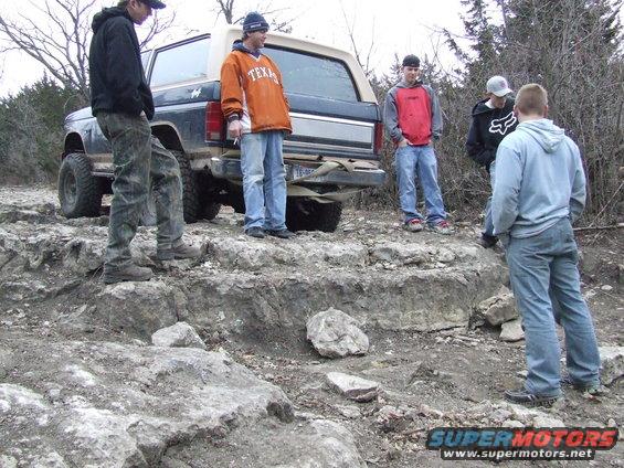 1986 Ford Bronco rear view with people standing around it on rocky terrain