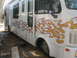 1977 Ford F-250 - A white motorhome is parked outdoors, prominent flame graphics along its side.