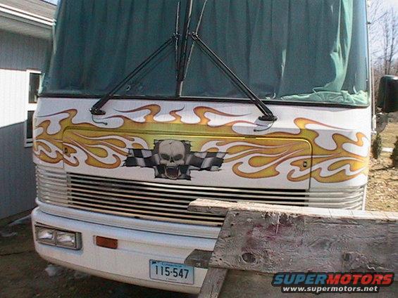 White RV front with flame graphics, skull, and checkered flag. License plate 115-547