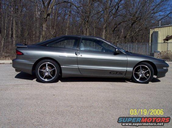 Side view of a gray 1995 Ford Probe GTS with aftermarket wheels parked on pavement