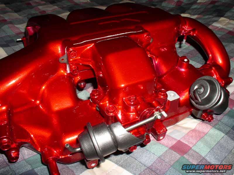 Red painted intake manifold with two actuators attached, resting on a checkered cloth