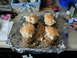 1979 Ford Bronco - Four baked potatoes topped with cheese sit on aluminum foil, ready for the oven.