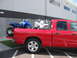 1980 Ford Bronco - A red pickup truck transports two all-terrain vehicles in its bed, viewed from the side.