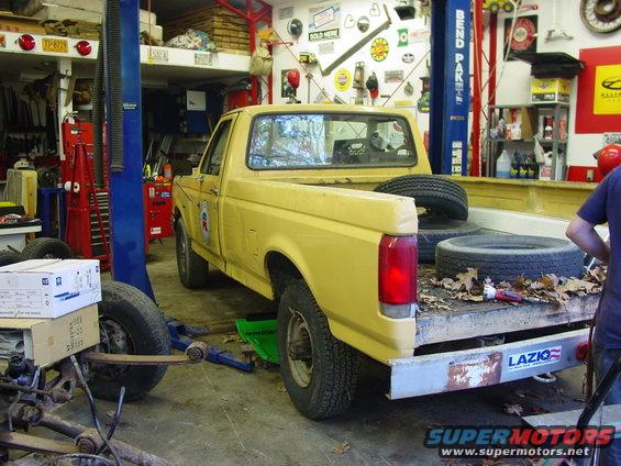 Yellow 1988 Ford F-250 pickup truck in garage, rear view