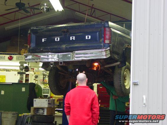 Ford pickup truck on a lift, rear view. Someone is working underneath