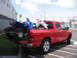 1980 Ford Bronco - A red pickup truck transports two ATVs, one blue and one white, with the tailgate lowered.