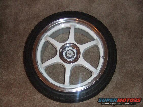 White 6-spoke alloy wheel with polished lip and black tire on carpet