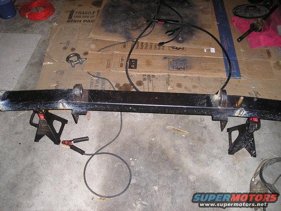 Black bumper on jack stands with welding cables attached
