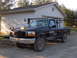 1995 Ford F-250 - This 1995 Ford F-250 pickup truck is equipped with a plow mount and a rack system, seen parked in front of a residential garage.