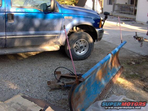 Blue Ford F-250 truck parked next to a blue snow plow. The truck has "F250" badging on the fender