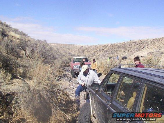 1978 Ford Bronco and other off-road vehicles navigating a rocky trail with brush on the sides