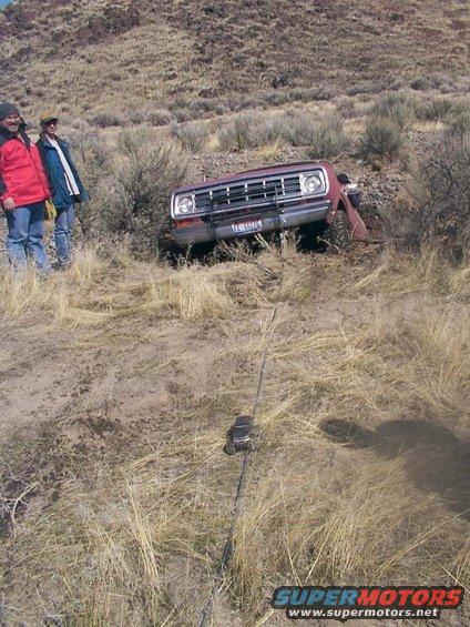 Red pickup truck stuck on a hillside, front view. License plate visible