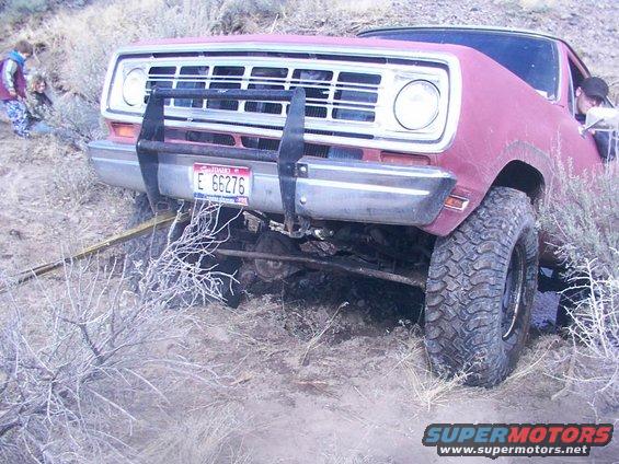 Red pickup truck with a brush guard stuck in dirt, license plate E 66276 visible