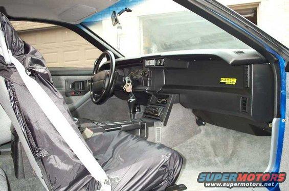 Interior view of a 1990 Chevrolet Camaro Z28 with a car cover on the driver's seat