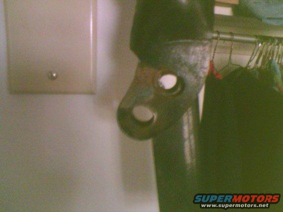 Close-up of a rusty metal bracket with two holes, possibly from a vehicle