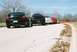 2004 Dodge SRT-4 - A line of cars, led by a black 2004 Dodge SRT-4, are parked on the side of a road.