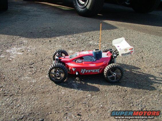 Red remote control car with "HYPER 7" text on the side, large rear spoiler, and visible engine