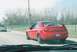 2004 Dodge SRT-4 - A red 2004 Dodge SRT-4 is seen from the rear, driving on a road with another car ahead.