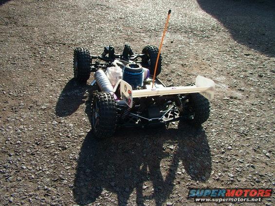 Radio-controlled car with blue engine and orange antenna on gravel