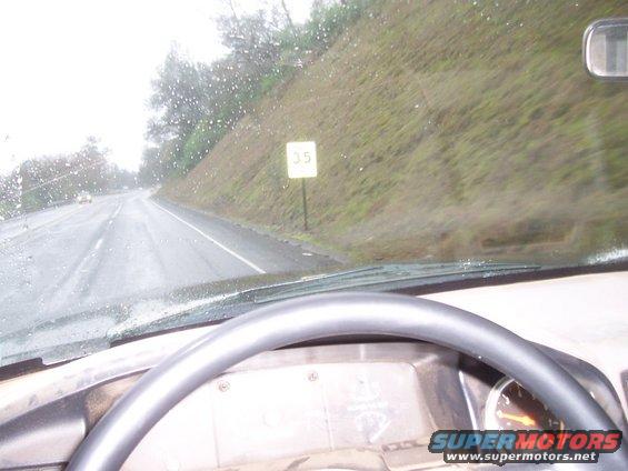 Interior view of a vehicle on a wet road with a 35 mph speed limit sign