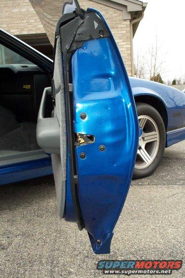 Blue Chevrolet Camaro door ajar, showing interior fabric and exterior paint. The front fender and wheel are visible
