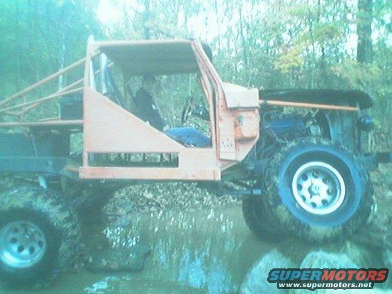 Modified off-road vehicle with roll cage, driving through mud and water