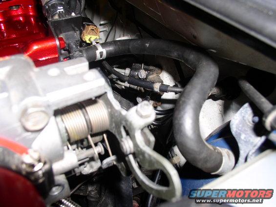 Close-up of engine throttle body with springs and hoses. Supermotors.net logo visible
