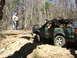 1996 Ford Bronco - A green off-road SUV navigates a challenging rocky terrain in a wooded area.