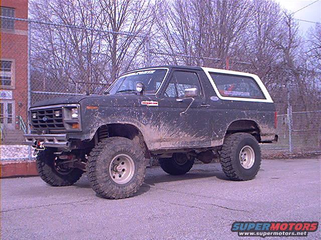 Dark lifted 1986 Ford Bronco with white top, muddy exterior