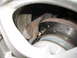 1996 Ford Probe - A close-up view of a rusty brake caliper positioned over a vented brake rotor, indicating a vehicle part.