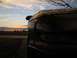 1996 Ford Probe - The back of a car is visible against a sunset sky with clouds and distant farm buildings.
