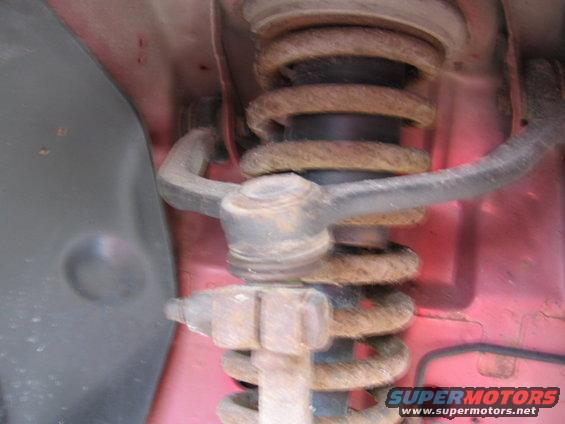 Close-up of a rusty suspension strut and coil spring assembly