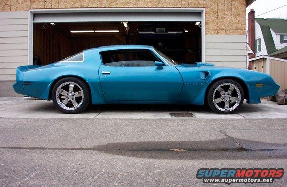 Blue coupe with custom chrome wheels parked in front of an open garage
