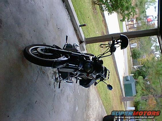 Black motorcycle parked under a covered area. Helmet on handlebars