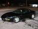 1981 Ford Mustang - A black Pontiac Firebird is parked outside a building at night with a person inside.