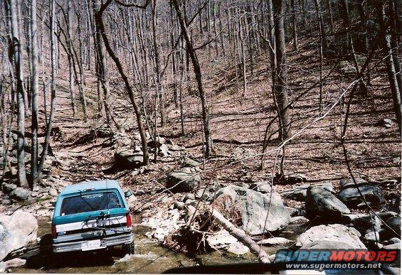 1987 Ford Bronco rear view, teal and white, driving off-road